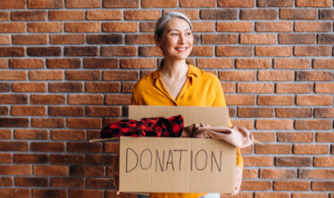 senior-woman-holding-cardboard-box-with-items-to-donate